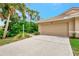 Beige home featuring a one-car garage, tile roof, and tropical landscaping in a well-maintained Florida neighborhood at 335 Auburn Woods Cir, Venice, FL 34292