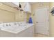 Well-lit laundry room with a washer and dryer, as well as shelving and an ironing board at 335 Auburn Woods Cir, Venice, FL 34292