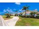 Home showcasing a well-maintained lawn, mature palm trees, and a circular driveway leading to the front entrance at 351 Eden Dr, Englewood, FL 34223