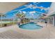 Serene screened pool area with a relaxing spa, offering picturesque lake views and a brick-paved patio at 351 Eden Dr, Englewood, FL 34223