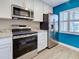 Modern kitchen featuring stainless steel appliances, white cabinets, and granite countertops complemented by a vibrant blue accent wall at 429 Cerromar Ln # 352, Venice, FL 34293