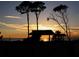 Silhouette of gazebo and trees at sunset, with a calm ocean and colorful sky enhancing the peaceful scene at 432 Sunset Lake Blvd # 205, Venice, FL 34292