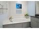 Bathroom with a soaking tub with gray cabinets and white quartz countertops at 48 Grande Fairway, Englewood, FL 34223