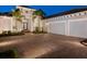 Paver driveway leading to a three car garage of a well-maintained home with lush landscaping at 48 Grande Fairway, Englewood, FL 34223