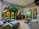 Covered outdoor space has a grill, comfortable seating, ceiling fan, and views of the golf course and sunset at 48 Grande Fairway, Englewood, FL 34223