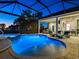 Screened-in pool with lights, spa, and outdoor seating area at dusk at 48 Grande Fairway, Englewood, FL 34223