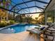 A relaxing outdoor pool and spa are complemented by cozy lounge chairs and beautiful landscaping at 48 Grande Fairway, Englewood, FL 34223