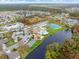 Community pool, tennis courts, shuffleboard, and clubhouse with a serene lake backdrop in an aerial view at 500 Wekiva River Ct # 129, Englewood, FL 34223