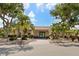 Community clubhouse featuring lush landscaping, benches, and clear signage on a sunny day at 500 Wekiva River Ct # 129, Englewood, FL 34223