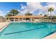 Community pool area featuring a pool, lounging chairs, and the community clubhouse building in the background at 500 Wekiva River Ct # 129, Englewood, FL 34223