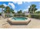 Community spa area with a tiled jacuzzi, surrounded by lush landscaping and a secure fence at 500 Wekiva River Ct # 129, Englewood, FL 34223