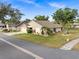 Charming single-story home with a well-manicured lawn and mature trees under a blue sky at 500 Wekiva River Ct # 129, Englewood, FL 34223
