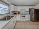 Bright kitchen featuring white cabinetry, white appliances, tile flooring, and a window with backyard views at 504 Buena Vista Dr, Nokomis, FL 34275