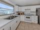 Bright kitchen featuring white cabinetry, white appliances, tile flooring, and a window with backyard views at 504 Buena Vista Dr, Nokomis, FL 34275