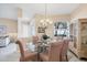 Sunlit dining room features a glass table, decorative chandelier, and a built-in display cabinet at 5223 Pine Shadow Ln, North Port, FL 34287