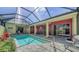 Covered lanai features a sparkling pool, patio seating, and a beautifully landscaped backyard at 525 Cheval Dr, Venice, FL 34292