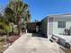 View of the side of the home with a driveway, palm trees, and a cozy outdoor seating area at 533 Cervina N Dr # 773, Venice, FL 34285