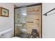 Bathroom features a shower with a glass enclosure, stone floors, and tiled walls at 612 Bird Bay S Dr # 311, Venice, FL 34285