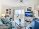 Cozy living room with comfortable seating, ceiling fan, and sliding glass doors to a screened patio with golf course views at 839 Wexford Blvd # 839, Venice, FL 34293