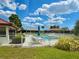 Community pool with white fence, lounge chairs, umbrella, landscaping, and nearby white villa buildings with red tile roofs at 846 Senda Plata # 26, Venice, FL 34293