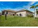 View of the backyard with green grass, palm tree and utilities, partially enclosed by a black chain link fence at 863 Southland Rd, Venice, FL 34293