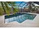 A screened in pool area with a waterfall feature and an outdoor dining set, surrounded by lush landscaping at 863 Southland Rd, Venice, FL 34293