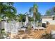 Back deck with white railing, wood decking, outdoor furniture, umbrella, and surrounding tropical foliage at 915 Citrus Rd, Venice, FL 34293
