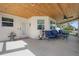 Covered porch with wood ceiling and blue seating overlooking the yard and garden at 915 Citrus Rd, Venice, FL 34293