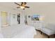 Bright bedroom with white dresser, ceiling fan, large window and view into en suite bath and walk-in closet at 925 Capri Isles Blvd # 4, Venice, FL 34292