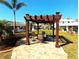 A wood pergola covers a patio area for relaxation with lush landscaping at 926 Inlet Cir, Venice, FL 34285
