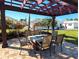 Pergola shaded outdoor dining area with a built-in fireplace and charming backyard views at 926 Inlet Cir, Venice, FL 34285
