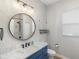 Charming bathroom with a blue vanity, marble countertop, and a round mirror at 109 Montelluna Dr, North Venice, FL 34275