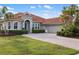 Beautiful home featuring a tile roof, arched entryway, lush landscaping, and a brick driveway at 109 Montelluna Dr, North Venice, FL 34275