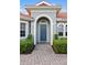 Beautiful front entrance with a blue door, well manicured landscaping, and a brick walkway at 109 Montelluna Dr, North Venice, FL 34275