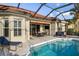 Outdoor pool features patio seating and dining, lounge chairs, and a covered area with a TV at 109 Montelluna Dr, North Venice, FL 34275