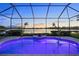 Screened-in pool glows blue at dusk with a view of the lake and landscaped yard at 109 Montelluna Dr, North Venice, FL 34275