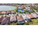 Aerial view of homes with screened pools, landscaping, with lake and tennis court in background at 11700 Tapestry Ln, Venice, FL 34293