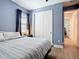 Cozy bedroom featuring wood floors, a window, closet, and a comfortable bed with soft blue walls at 11700 Tapestry Ln, Venice, FL 34293