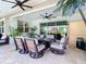 Covered patio with tile flooring, ceiling fans and dining table with cushioned chairs and manicured greenery at 11700 Tapestry Ln, Venice, FL 34293
