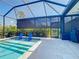 Enjoy the screened-in pool with blue Adirondack chairs, travertine tile, and a peaceful backyard setting at 11700 Tapestry Ln, Venice, FL 34293