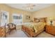 Comfortable bedroom featuring a wooden bed frame, wicker chair, and natural lighting at 121 Auburn Woods Cir, Venice, FL 34292