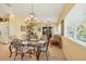 Well-lit dining area with glass top table and a decorative chandelier, adjoining the living area at 121 Auburn Woods Cir, Venice, FL 34292