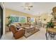 Cozy living area features a ceiling fan, comfortable seating, and large windows for natural light at 121 Auburn Woods Cir, Venice, FL 34292