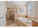 Bright bathroom showcasing a walk-in shower and a soaking tub with travertine tile surround at 13215 Amerigo Ln, Venice, FL 34293