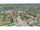 Grand entrance to a gated community featuring lush landscaping, a clubhouse, and a pristine lake at 13215 Amerigo Ln, Venice, FL 34293