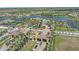 Aerial view of a grand community entrance with lush landscaping, a pool, and tennis courts at 13215 Amerigo Ln, Venice, FL 34293