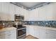 Corner view of a kitchen featuring white cabinets, quartz countertops, stainless steel appliances, and tile backsplash at 13215 Amerigo Ln, Venice, FL 34293
