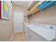 Functional laundry room with white washer and dryer, overhead storage, and tiled flooring at 13215 Amerigo Ln, Venice, FL 34293