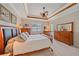 Comfortable main bedroom featuring tray ceilings, a ceiling fan, and plenty of natural light at 13215 Amerigo Ln, Venice, FL 34293