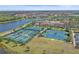 Aerial view of the community's tennis and pickleball courts with the pool and lake in the background at 13215 Amerigo Ln, Venice, FL 34293